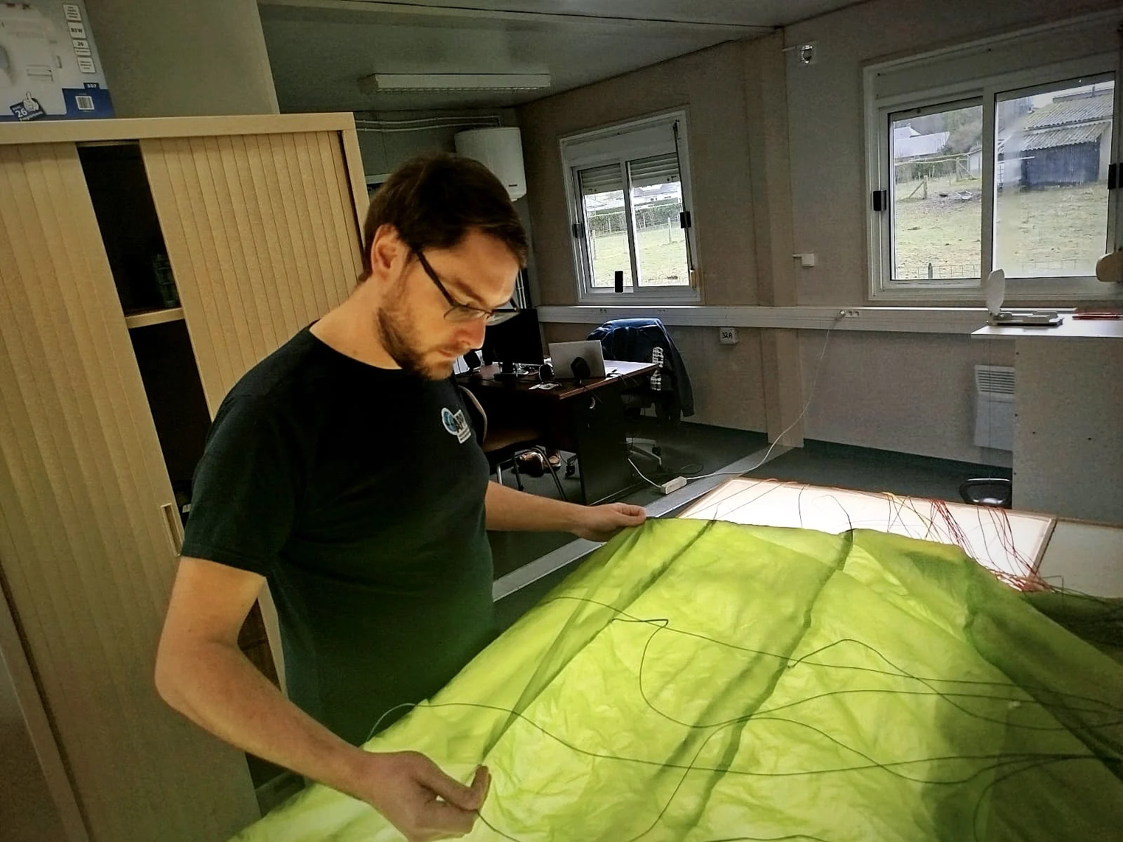 Inspection d’une voile de parapente sur la table lumineuse de l’atelier ReviFly76